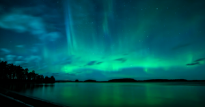 Image of a lake with a green and blue auroral borealis sky